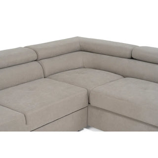 The PF Sofas SOFAINSTORE Ferrano Beige Fabric Corner Sofa Bed is L-shaped with wide cushioned seats, a low padded backrest, hidden storage, and a fold-out sleeper.