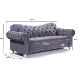 The Beehive Furniture Jubilee Grey Velvet 3 Seater Sofa features button-tufted elegance and modern design, with rolled arms and studded trim. Dimensions: 220x86x90cm; seat 160x60x50cm; back height 55cm. Ideal for stylish living rooms.