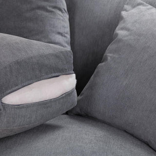 Close-up of a plush gray chair with overstuffed cushions, mirroring the style of the Beehive Furniture Windsor Fullback Grey Corner Sofa (Left Hand Facing, Button-Tufted Arms); one cushion shows its white inner padding through a partly open zipper.