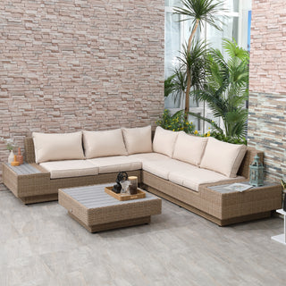 A stylish patio showcases the Outsunny 4 PCs Rattan Garden Furniture Set, featuring a wicker sectional sofa with beige cushions, matching coffee table, armrests, and decorative accents—all set against brick and tile walls.