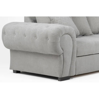 The PF Sofas SOFAINSTORE Grey Fabric Chesterfield Corner Sofa Bed features classic scroll arms, a pull-out sleeper, storage, and multiple matching cushions for comfort. Upholstered in light grey fabric with sturdy square dark wooden legs.