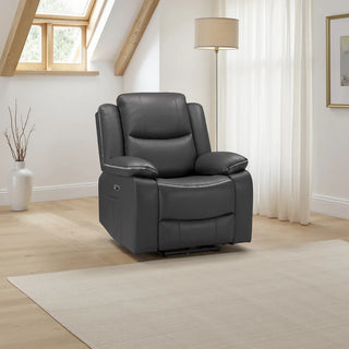 A modern living room features the Beehive Furniture SOFAINSTORE Harald Black Leather Electric Recliner Armchair with power recline and contrast stitching on a light wood floor and beige rug, accented by a lamp, white curtains, framed art, and a vase by the window.