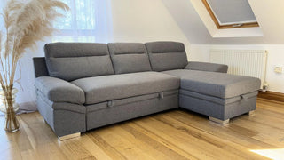 The Beehive Furniture SOFAINSTORE Astoria Grey Fabric Corner Sofa Bed with Storage Chaise and pull-out guest bed adds modern luxury and space-saving style to your bright living room, perfectly complementing wooden floors and contemporary décor.
