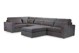 The Kiana Modular Sofa by Beehive Furniture is a large, L-shaped grey fabric corner sofa with plush cushions and an attached ottoman, offering versatile seating in a sleek modular design.