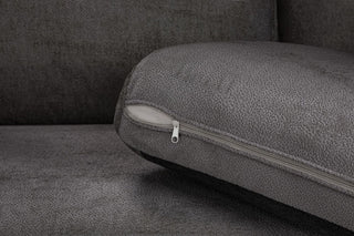 A close-up of a gray fabric cushion with a visible zipper, highlighting the textured upholstery and part of the Beehive Furniture Kiana Modular Sofa | Grey Fabric | Large Corner Design in the background.