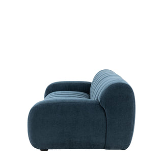 Side view of the Gallery Direct Coste Fabric 3 Seater Sofa, featuring plush blue upholstery, retro-inspired rounded arms and back, and horizontal tufted detailing. Isolated on a white background.