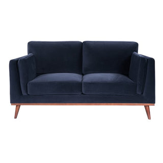 The Maili Velvet Fabric 2 Seater Sofa by Twenty Ten Designs, shown in midnight blue with boxy armrests and angled wooden legs, offers cushioned comfort and is displayed from the front against a white background.