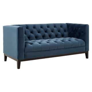 The Okab Velvet 2 Seater Sofa by Premier Sofas features midnight blue tufted upholstery, a high back and sides, button details, and dark wood legs—all shown at an angle against a white background.