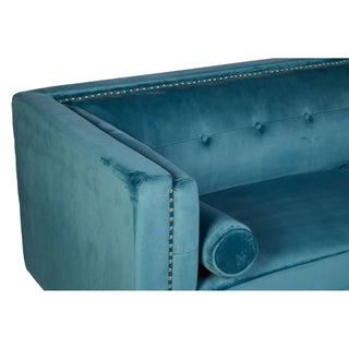 The Felisen Upholstered Velvet 3 Seater Sofa by Premier Sofas features blue velvet, button tufting, silver nailhead trim, and matching bolster pillow—a stylish choice with a sturdy frame for any modern living room.