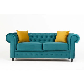The PF Sofas SOFAINSTORE Florencia Ocean Teal Chesterfield 2 Seater, featuring luxe velvet, scroll arms, and button tufting, is styled with two mustard yellow throw pillows against a plain white background.