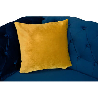 A square yellow velvet pillow rests on the PF Sofas SOFAINSTORE Florencia Navy Blue Velvet Chesterfield 2 Seater Sofa with scroll arms and button tufting.