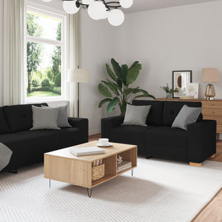 Modern living room featuring the vidaXL 3-Piece Sofa Set with Cushions in Black Fabric, gray and white pillows, a light wood coffee table, large windows with sheer curtains, a tall green plant, and soft lighting from floor and ceiling lamps.