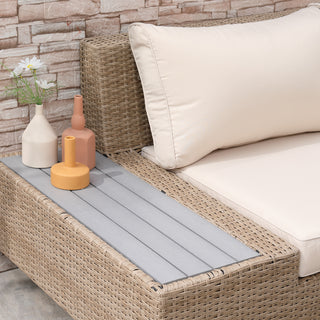 The Outsunny 4 PCs beige rattan garden sectional sofa and coffee table set, styled with three vases—cream, orange, yellow (one holding white daisies)—is arranged against a stone-patterned wall.
