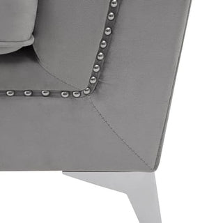 Close-up of the Hefei Velvet 2 Seater Sofa by Premier Sofas, featuring grey fabric upholstery, chrome metal legs, and stylish nailhead trim. A cushion sits in the upper left, highlighting this modern living room piece.
