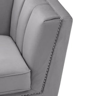 Close-up of a modern gray upholstered armchair with vertical tufting and silver nailhead trim, beautifully matching the Hefei 3 Seater Sofa in grey velvet from Premier Sofas, featuring chrome metal legs and chic design.
