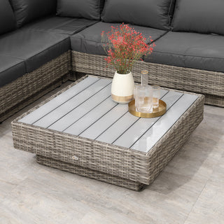 The Outsunny 4 PCs Rattan Garden Furniture Set in light grey features a coffee table with a glass top holding a vase of pink flowers and a gold tray with decanters, surrounded by cushioned sectional seating on a tiled floor.