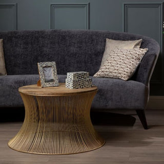 A modern living room with the Premier Sofas Contemporary 3 Seater Sofa in grey velvet and slim black legs, two patterned cushions, a round gold wire coffee table with mosaic boxes and a photo frame, set against paneled gray walls and wood flooring.