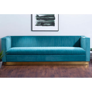 The Premier Sofas Contemporary Light Blue Velvet 3 Seater Sofa with a gold base and tufted design sits on a wooden floor. Above, a minimal abstract black-and-white painting hangs on the white wall, with a small plant partially visible on the left.