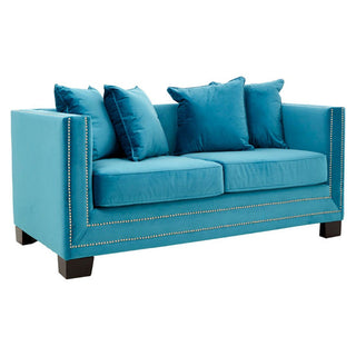 The Pipirima Upholstered Velvet 2 Seater Sofa by Premier Sofas features cyan blue fabric, plush comfort, square arms, silver nailhead trim, dark wooden legs, and four matching throw pillows.